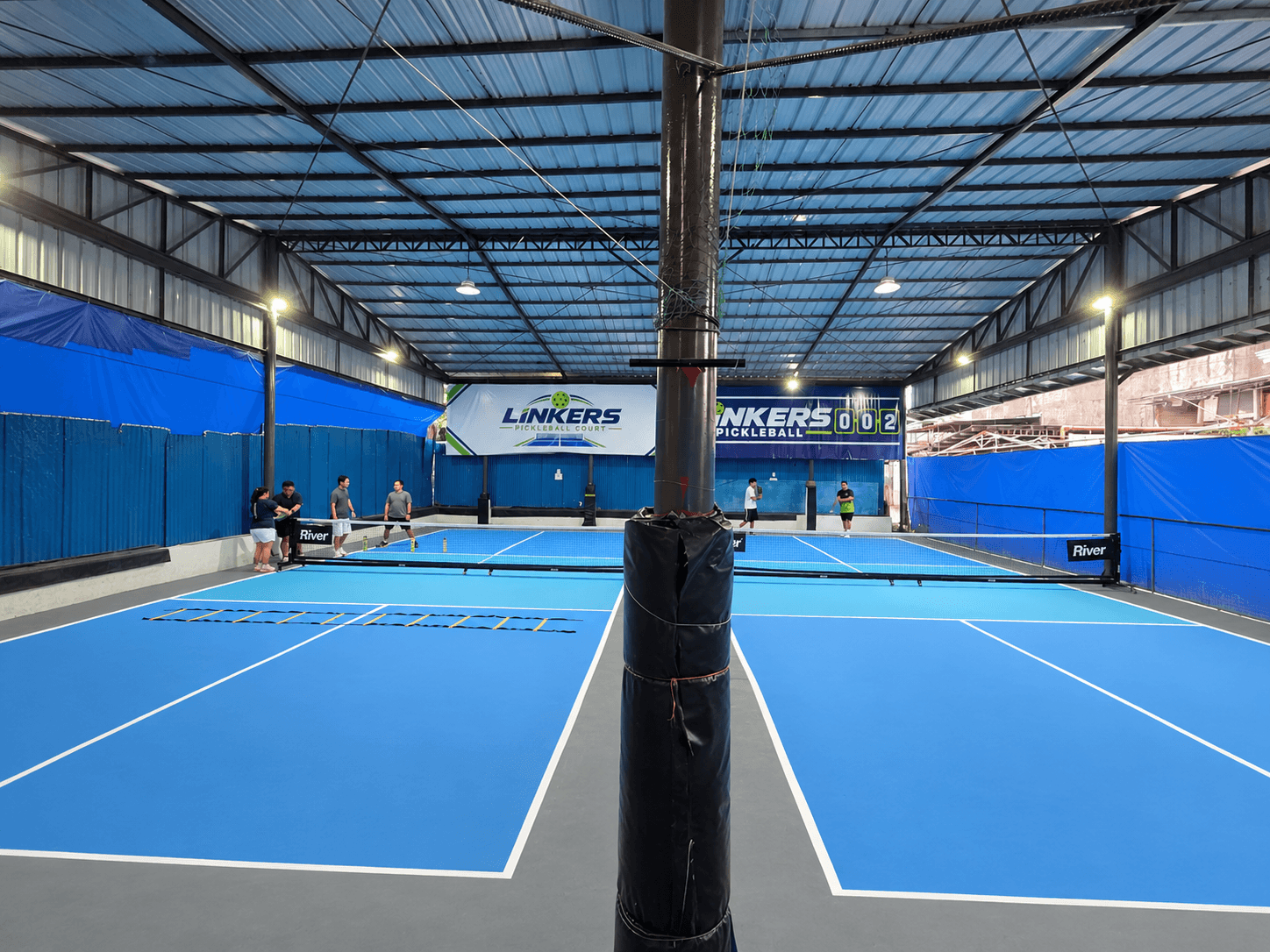 Court 4 — blue pickleball court under the covered steel-roofed pavilion